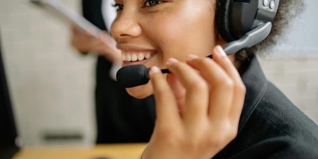 Portrait of a smiling call center agent wearing a headset in an office setting.
